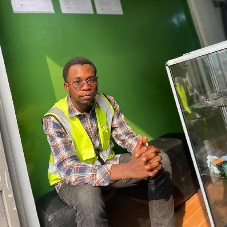 Guelord Mwenderwa, seated, wearing a high-visibility vest